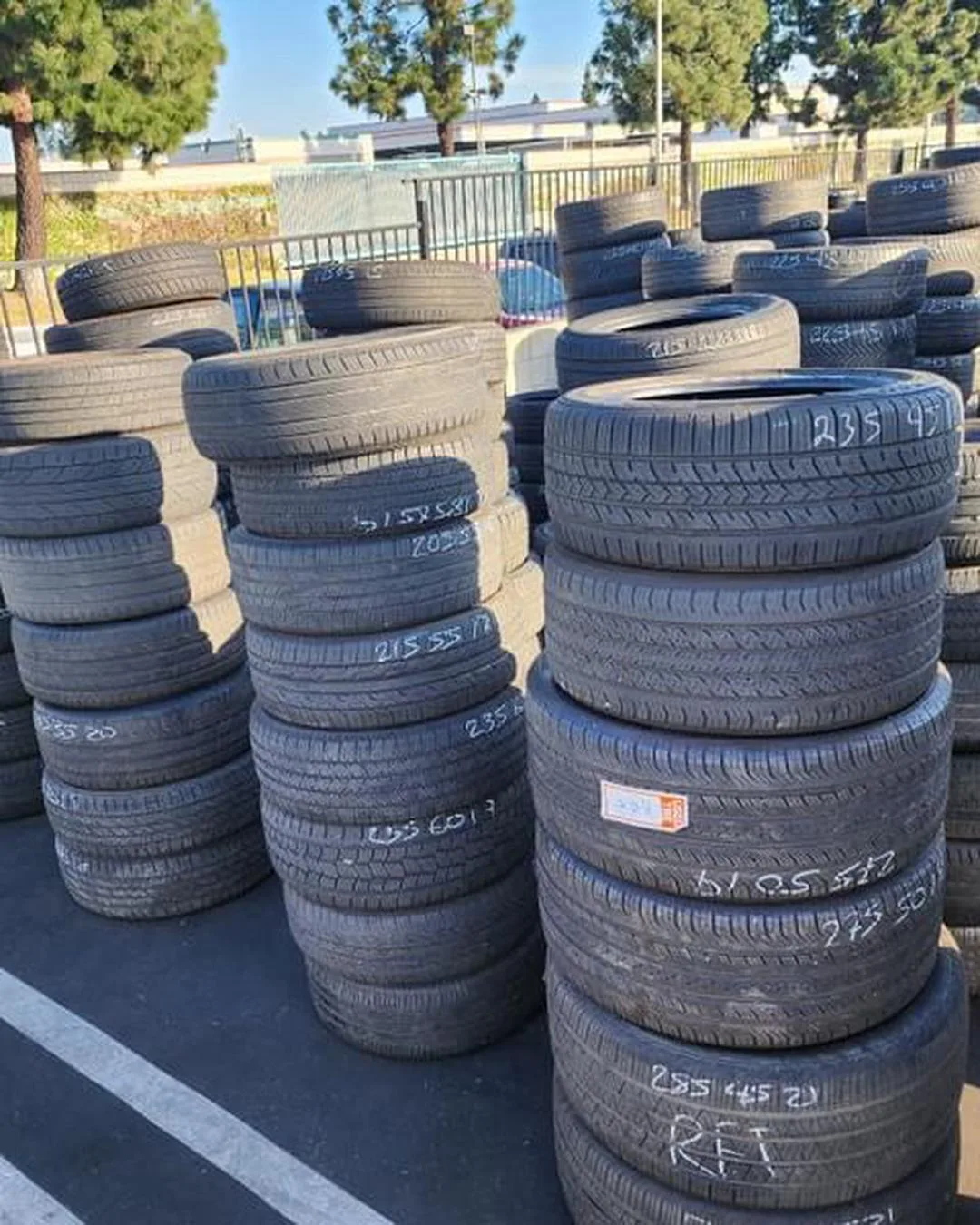Stacked used tires with sidewall sizes marked